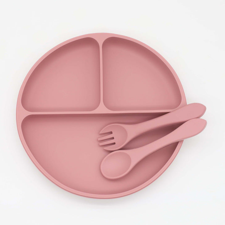 Assiette à dîner ronde en silicone pour bébé avec ventouse et compartiments, accompagnée d'une cuillère et d'une fourchette.